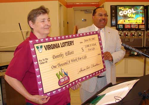 Dorothy Elliott of Norfolk receives her souvenir lottery check from Virginia Lottery Deputy Director Richard Williams.